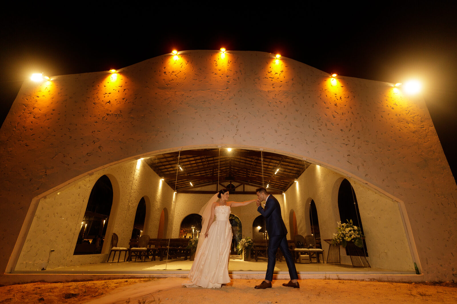 Casal dançando sob o pavilhão iluminado, à noite.